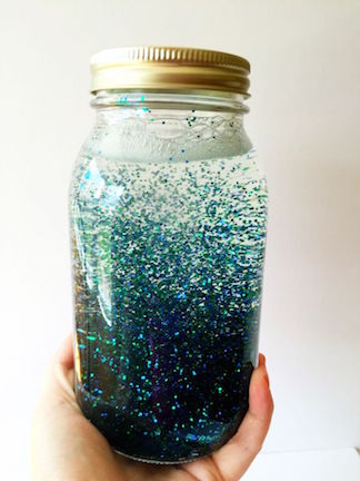 Person holding a jar of water filled with glitter